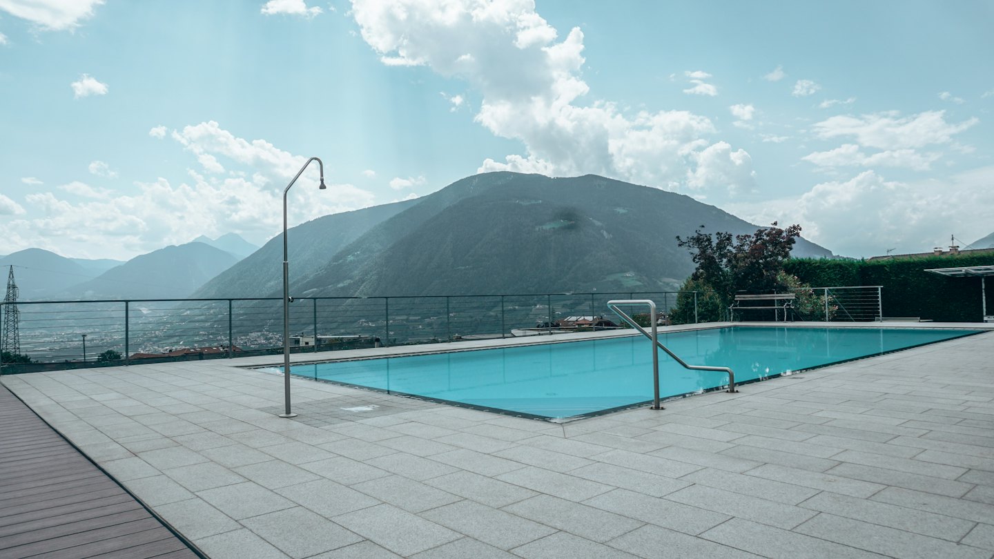 An outdoor pool overlooking mountain ranges and a valley town.