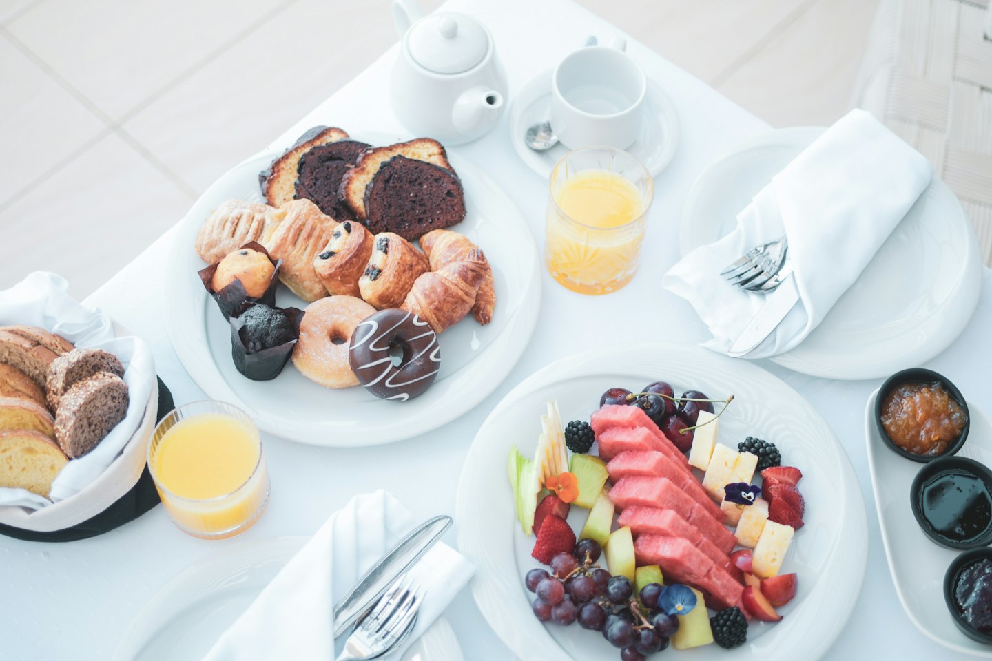 A breakfast spread of pastries, fruit, and tea on a table.