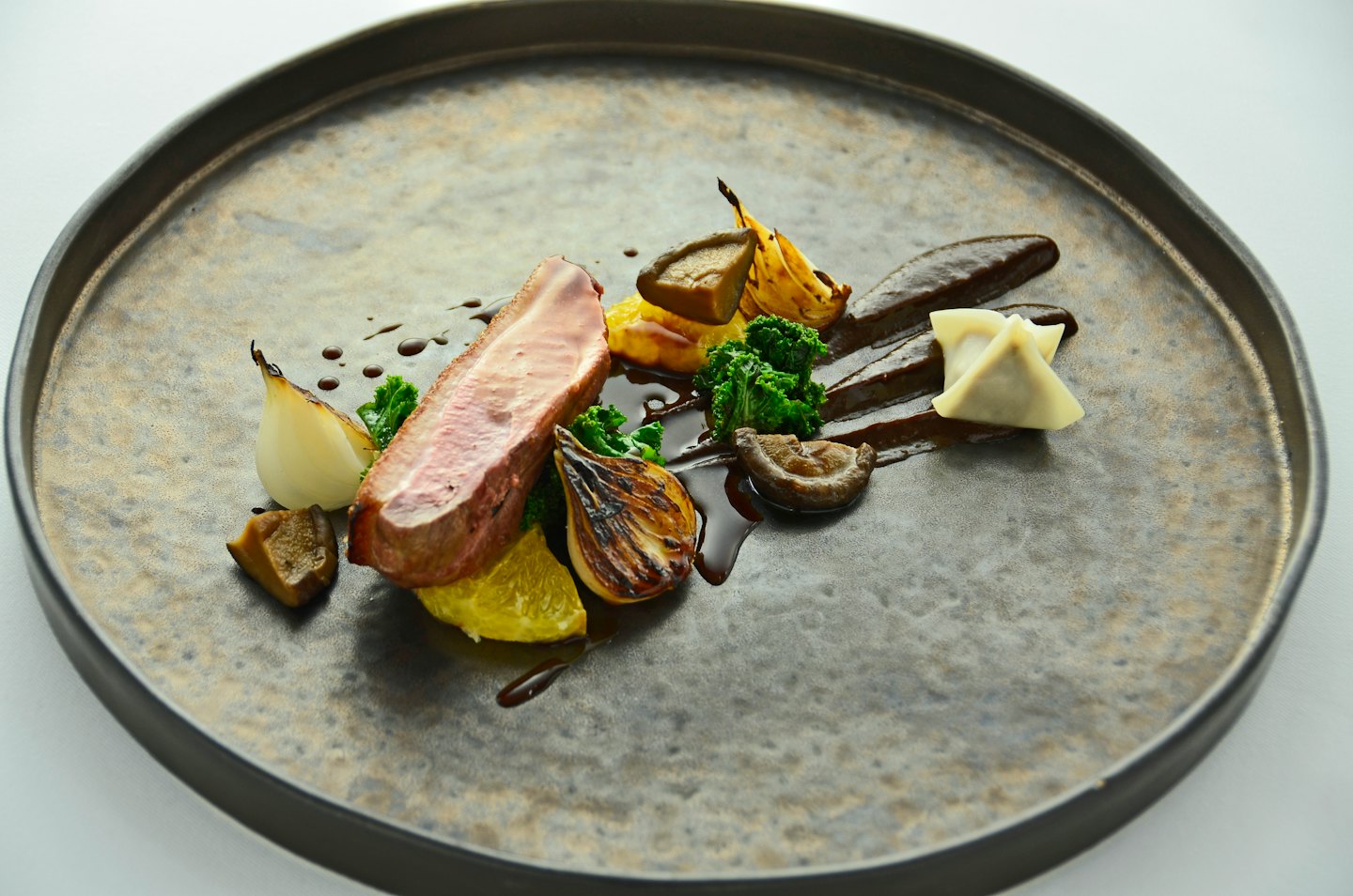 Seared duck breast with broccoli, onions, and mushrooms on a plate.