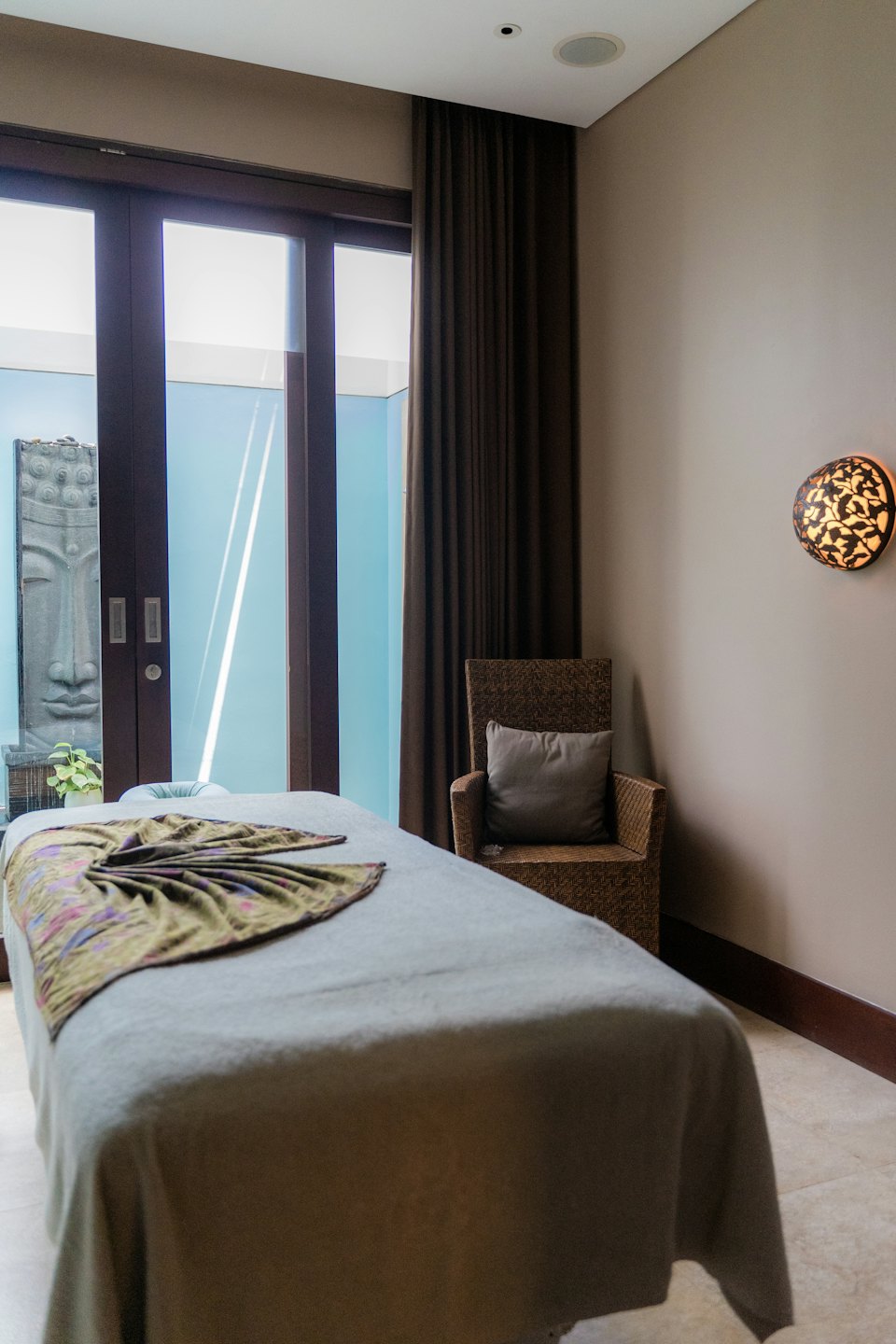 Empty spa room with massage bed and Buddha statue.