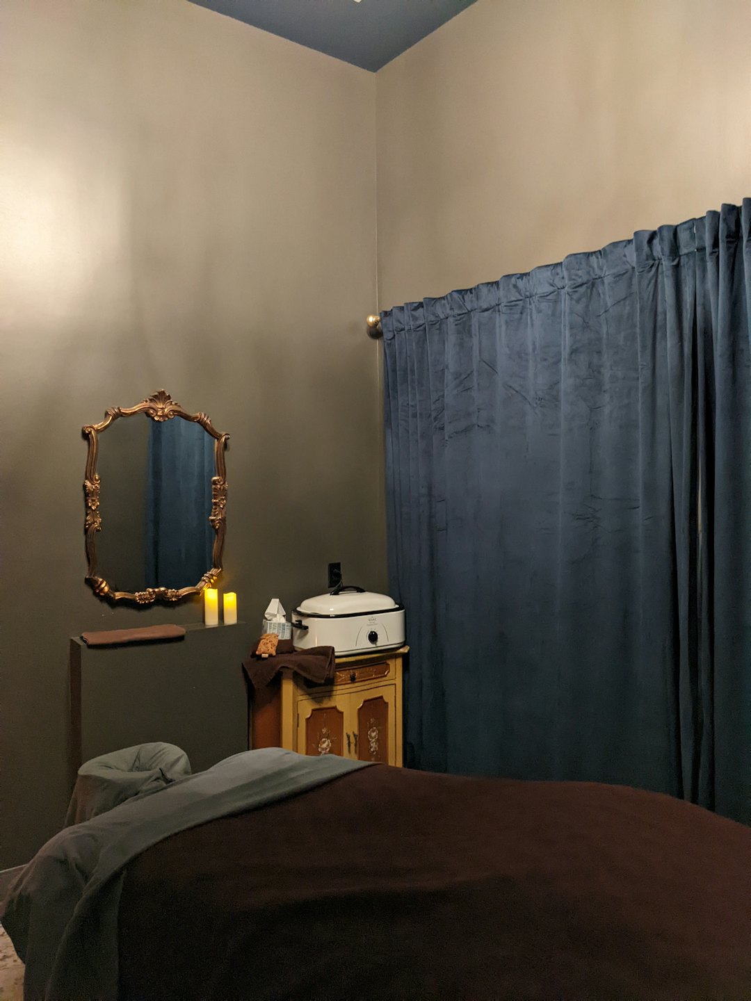 Serene massage room with a made bed and glowing candles.