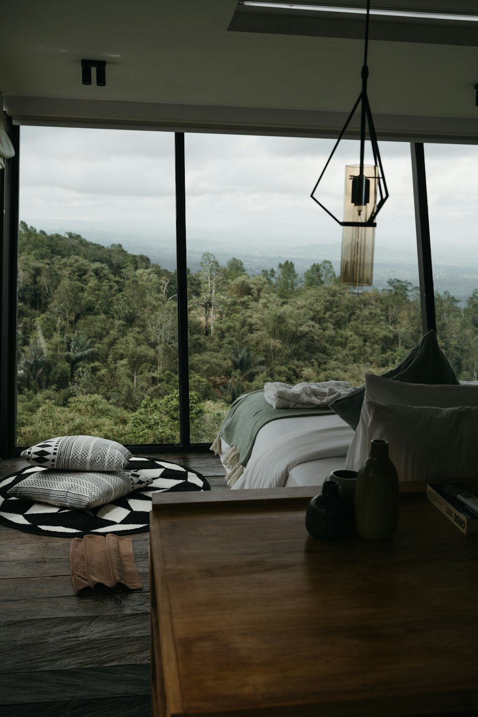 Bedroom with large window overlooking a forest.