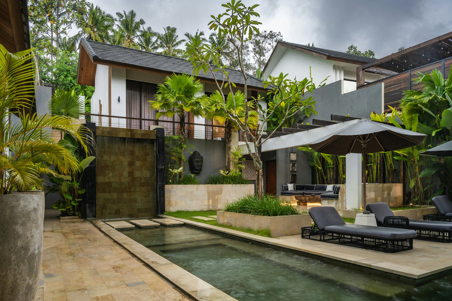 Modern villas surround a resort swimming pool and lounge area.