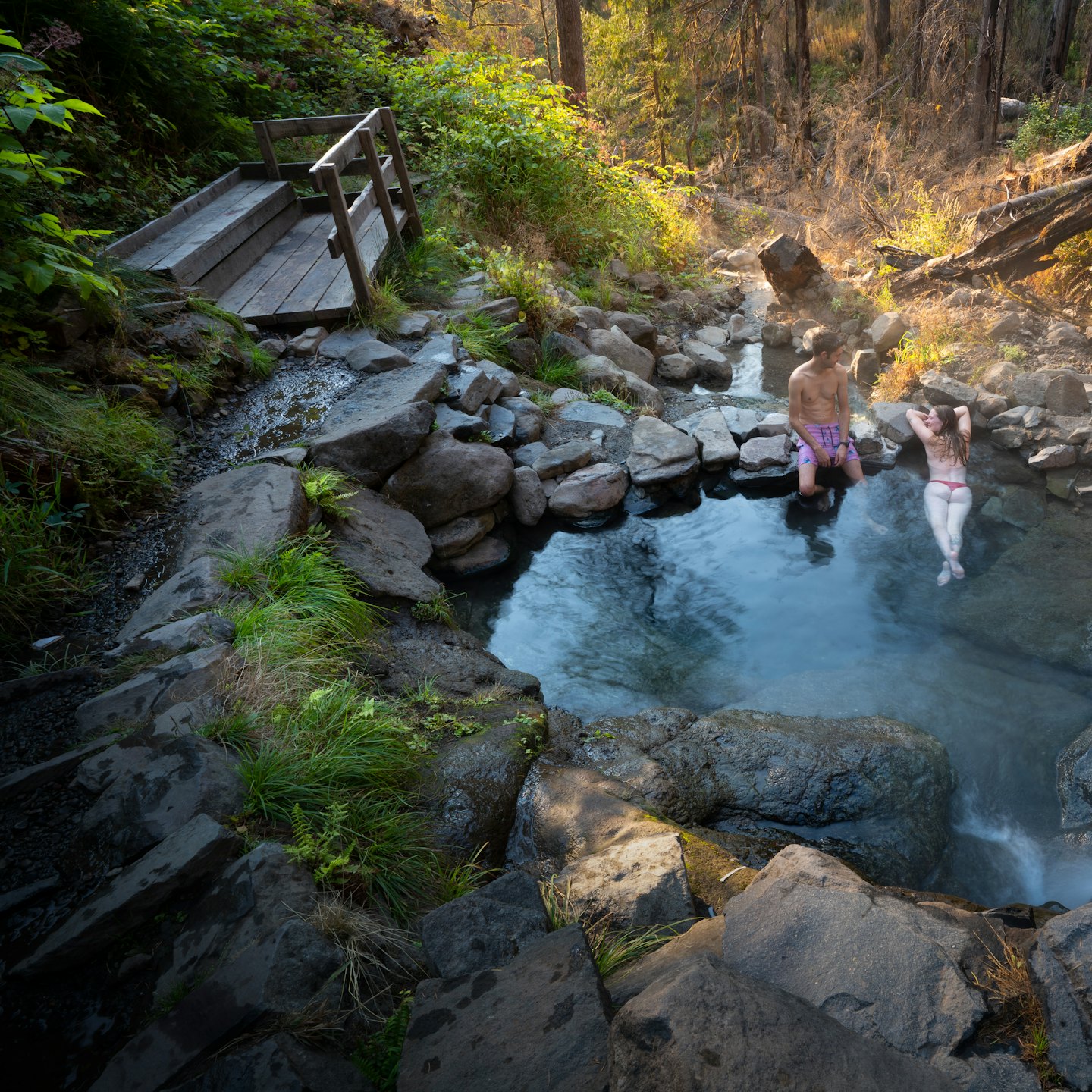 Couple relaxing in a sun-dappled natural hot spring.